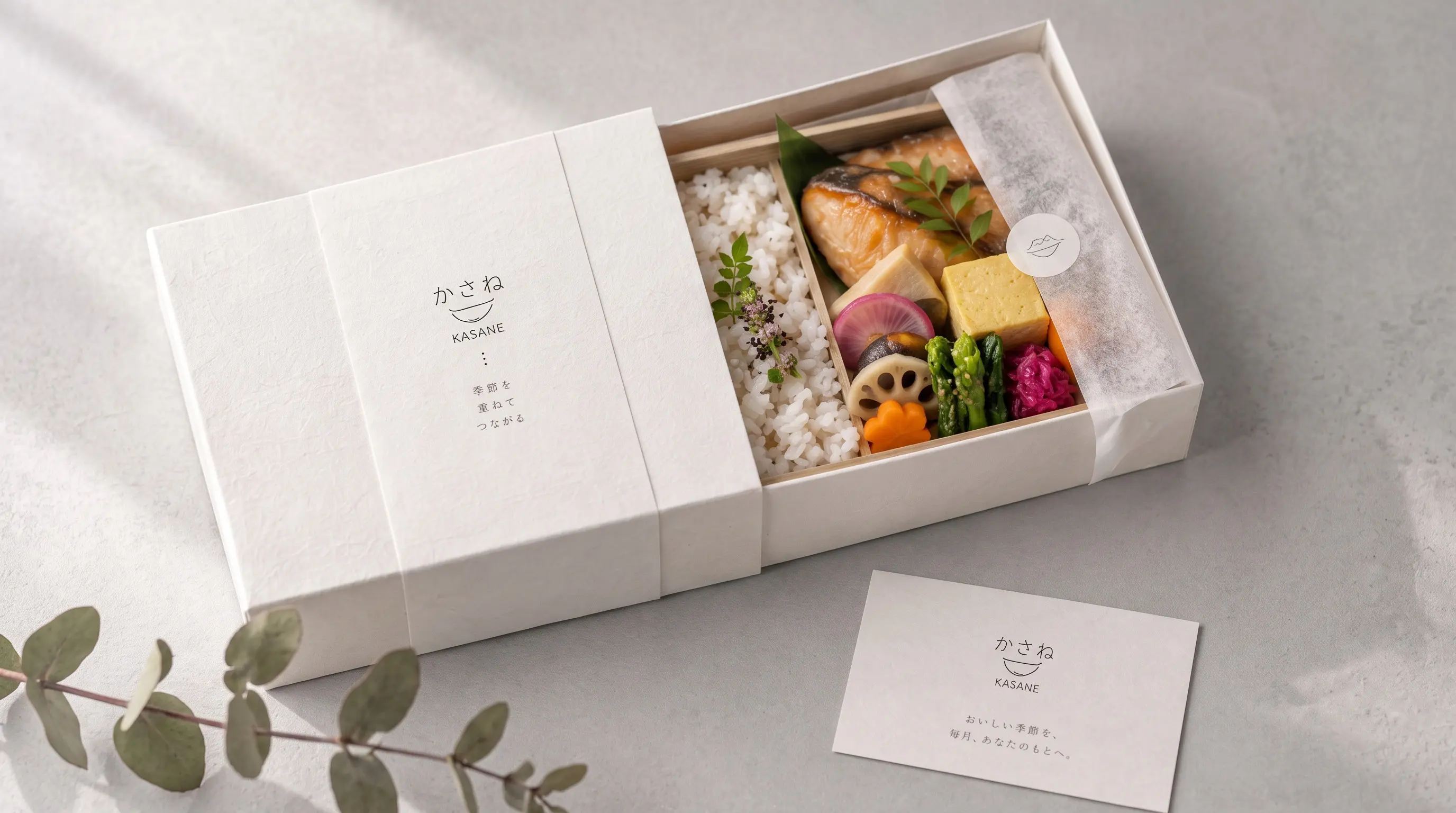 A KASANE bento transitioning from its closed sleeve to a colourful open meal