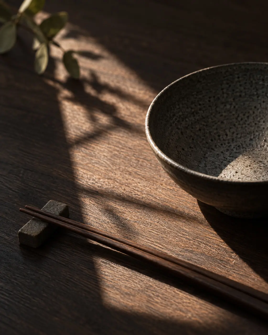 Wooden chopsticks and ceramic bowl in warm, dappled light